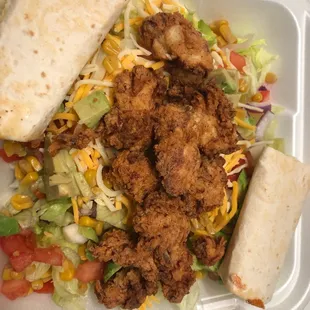 a chicken burrito and a salad in a styrofoam container