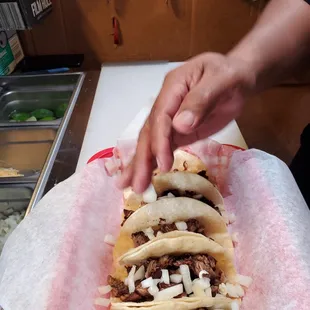 a person putting toppings on a taco