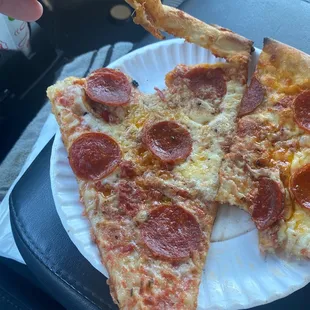 two slices of pepperoni pizza on a paper plate
