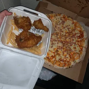 a hand holding a box of chicken