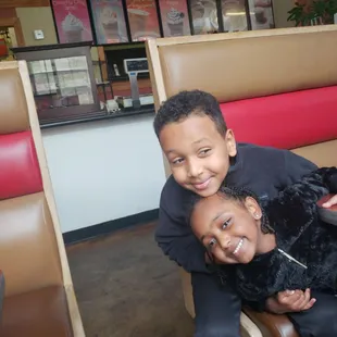 a boy and a girl sitting in a booth