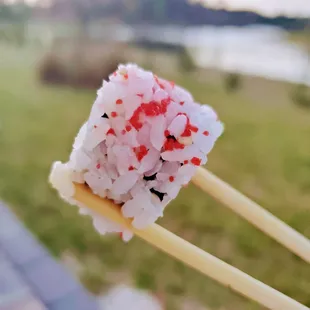 chopsticks holding a piece of sushi