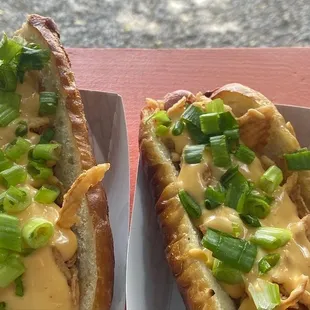 two hot dogs with cheese and green onions