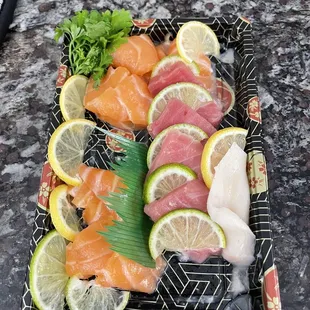 a platter of sushi and lemon slices