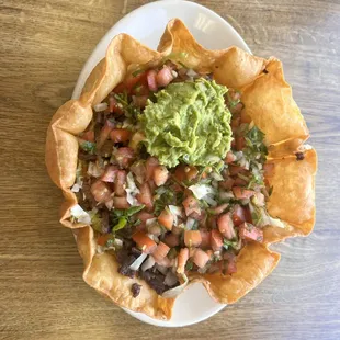 Carne asada tostada bowl served with tomato relish (pico de gallo) and fresh guacamole