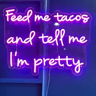 a neon sign that reads feed me tacos and tell me i'm pretty