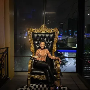 a woman sitting on a throne in front of a window