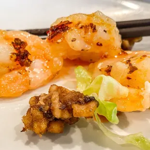 shrimp and lettuce on a plate with chopsticks