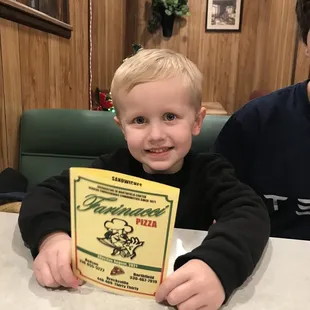 a young boy holding a menu