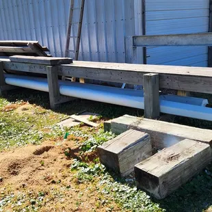 Two white masts in progress resting under an outdoor bench.
