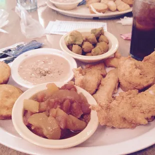 a plate of fried chicken, potatoes, and other foods