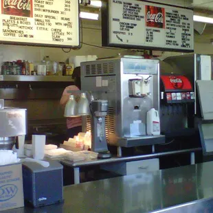 a restaurant counter with a menu on the wall