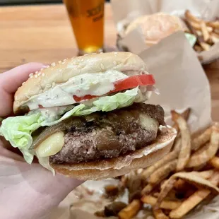 a hand holding a hamburger and fries