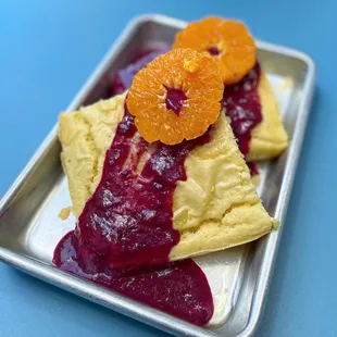 a plate of crepes with oranges on top