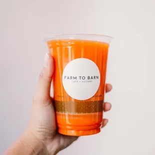 a hand holding a cup of orange juice