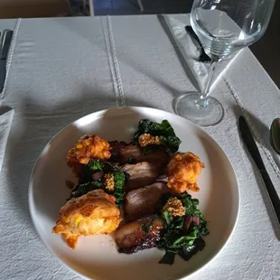 Pork belly with corn fritters and local sautéed greens at Farmacy Grill