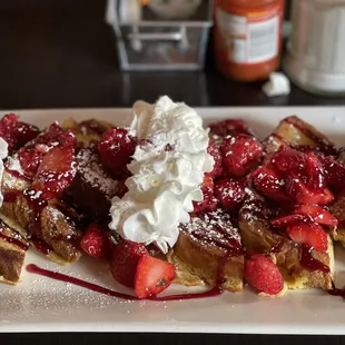 a plate of waffles with strawberries and whipped cream