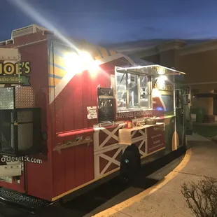 a red food truck parked in front of a building