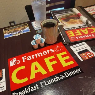 a table with a sign and a cup of coffee