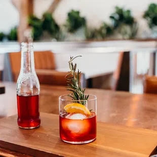 a glass of wine and a bottle of soda on a table