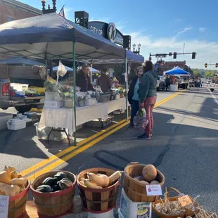 a woman standing under a tent selling produce