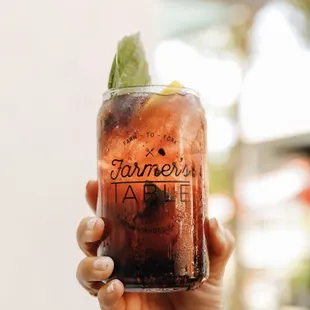 a hand holding a jar of iced tea