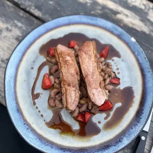 a plate of meat and beans on a wooden table