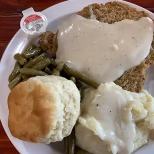Chicken fried steak, mashed potatoes with gravy, green beans, and a homemade biscuit