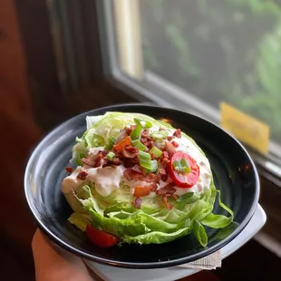Iceberg wedge salad with gorgonzola blue cheese, cherry tomato and green onion.