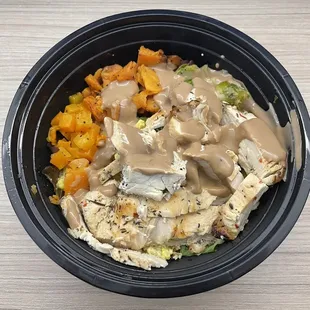 a bowl of food with chicken, broccoli, carrots and gravy