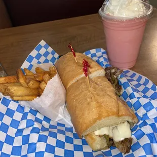 Philly cheese steak with fries and strawberry milkshake.