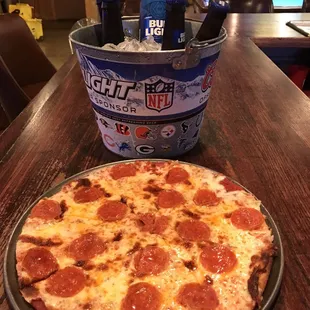 a pepperoni pizza and a bucket of beer
