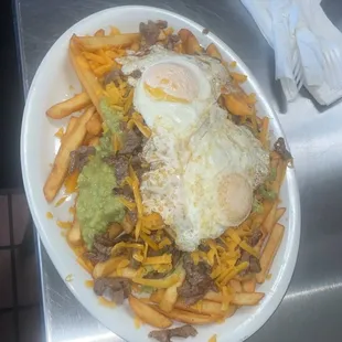 Carne asada fries with egg on top includes guacamole, sour cream, chesse &amp; 2 eggs
