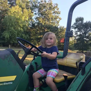 a little girl driving a tractor