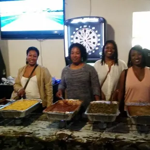 a group of women standing in front of a table full of food