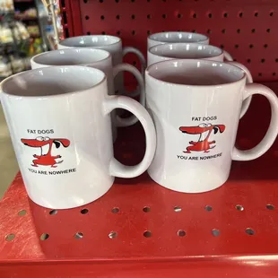 three coffee mugs on a red shelf
