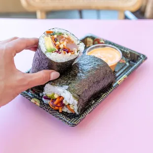 a hand holding a piece of sushi