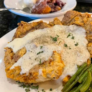 a plate of chicken with gravy and green beans