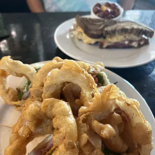 Onion rings club sandwich underneath and a Rueben sandwich with fresh fruit