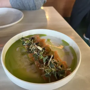 a bowl of soup with a piece of fish in it