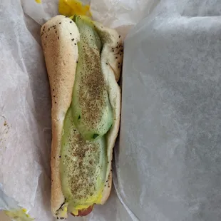 a hot dog with pickles and mustard