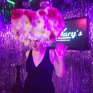  a woman in a black dress with a large fan on her head