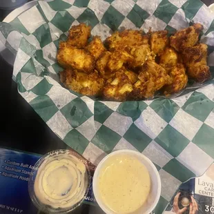a basket of fried chicken with a side of mustard