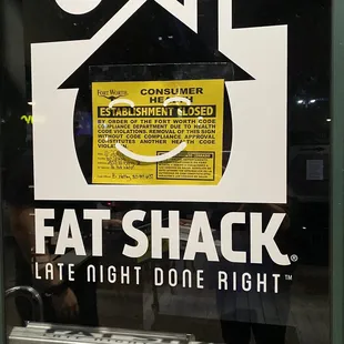 a man standing in front of a fat shack sign