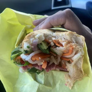 a person holding a sandwich in a wrapper