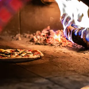 a pizza cooking in a brick oven