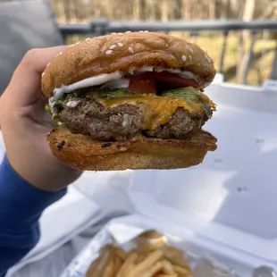 a person holding a hamburger and french fries