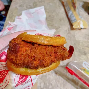 a hand holding a fried chicken sandwich