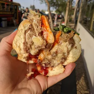 a hand holding a half eaten sandwich