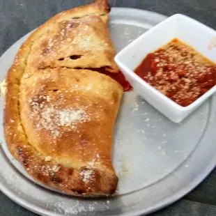 Perfectly baked calzone with extra sauce on the side if you ask